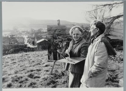 Marie Hartley and Joan Ingilby. Marie standing by (?painting) the big picture of Askrigg (December 1984)